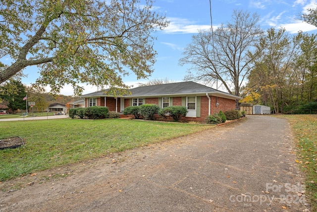 ranch-style home featuring a shed and a front lawn