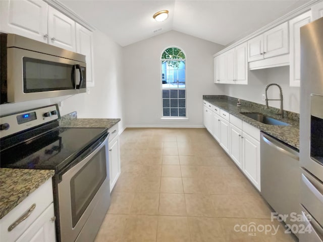 kitchen with lofted ceiling, sink, white cabinets, light tile patterned flooring, and appliances with stainless steel finishes