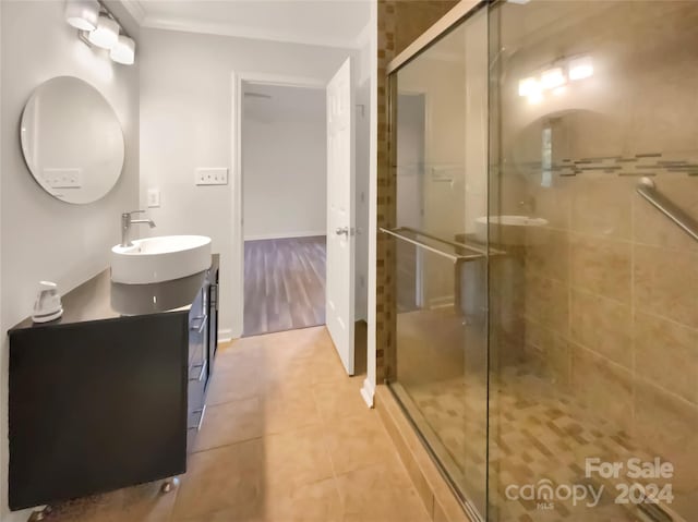 bathroom featuring vanity, crown molding, walk in shower, and tile patterned floors