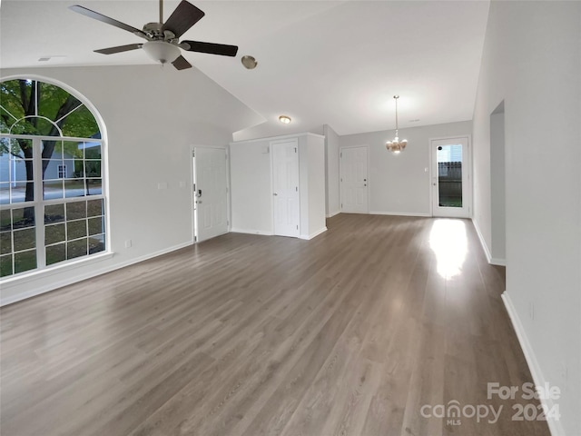 unfurnished living room featuring high vaulted ceiling, a wealth of natural light, ceiling fan with notable chandelier, and hardwood / wood-style floors