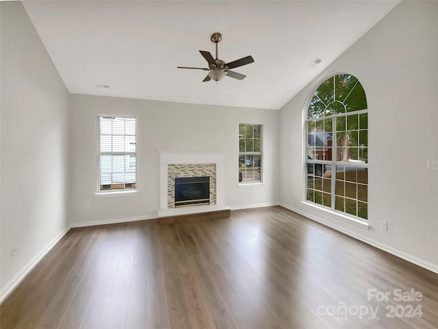 unfurnished living room with a tiled fireplace, vaulted ceiling, dark hardwood / wood-style flooring, and ceiling fan