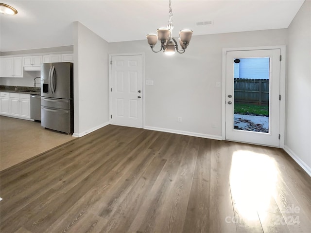 unfurnished dining area with an inviting chandelier, sink, and dark hardwood / wood-style floors