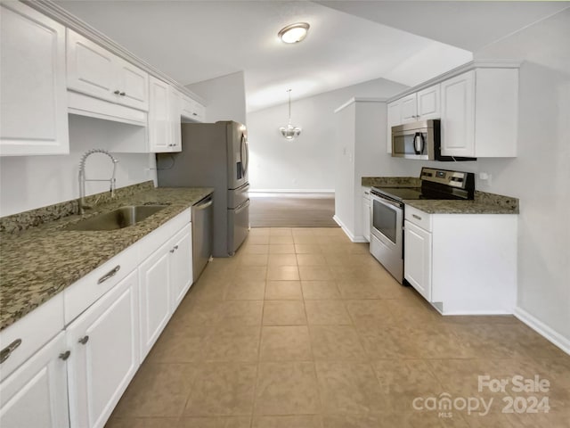 kitchen featuring dark stone counters, sink, vaulted ceiling, white cabinetry, and appliances with stainless steel finishes