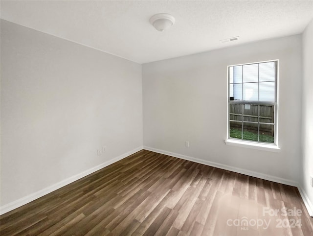 unfurnished room with a textured ceiling and dark hardwood / wood-style flooring