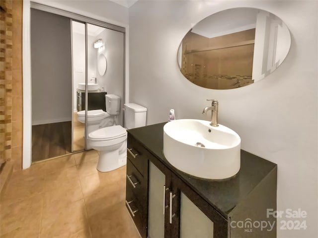 bathroom with toilet, walk in shower, vanity, and tile patterned flooring