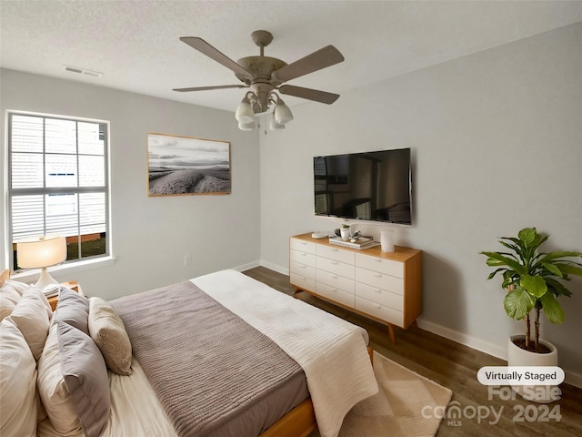 bedroom featuring dark hardwood / wood-style flooring, a textured ceiling, and ceiling fan