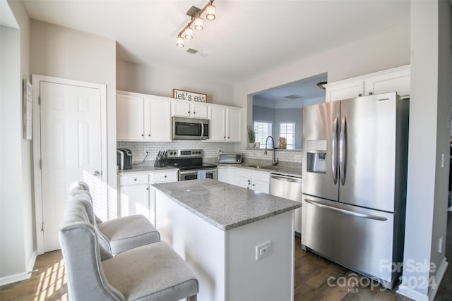 kitchen with white cabinets, sink, a kitchen island, dark hardwood / wood-style flooring, and stainless steel appliances