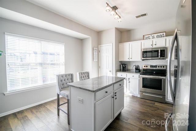 kitchen featuring appliances with stainless steel finishes, dark hardwood / wood-style floors, white cabinetry, and a kitchen island