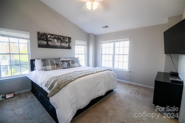 bedroom featuring ceiling fan, vaulted ceiling, light colored carpet, and multiple windows