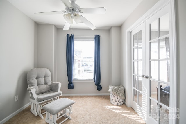 living area with light carpet, french doors, and ceiling fan