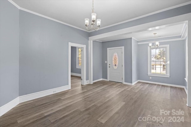 foyer entrance with ornamental molding, a notable chandelier, and hardwood / wood-style flooring