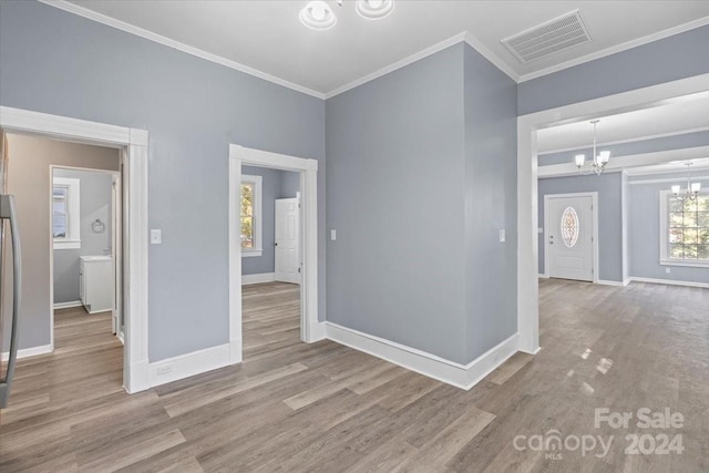 unfurnished room with crown molding, light hardwood / wood-style flooring, and an inviting chandelier