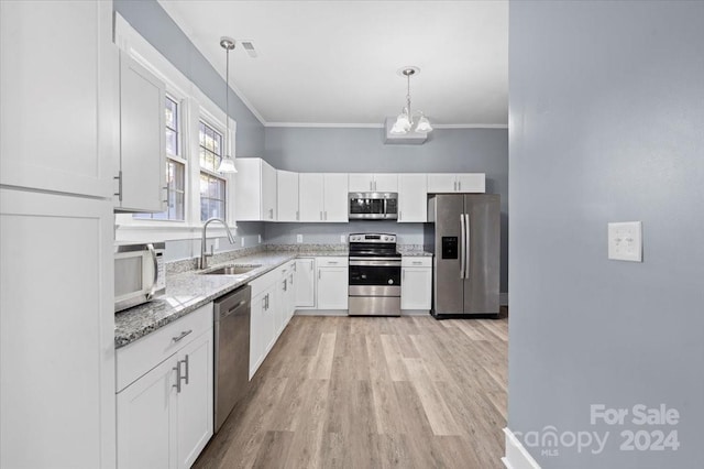 kitchen featuring appliances with stainless steel finishes, sink, hanging light fixtures, white cabinetry, and light hardwood / wood-style flooring