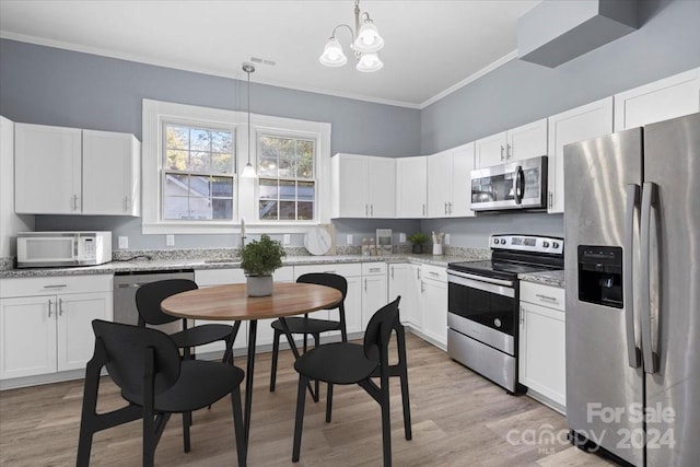 kitchen with appliances with stainless steel finishes, white cabinetry, pendant lighting, crown molding, and light hardwood / wood-style flooring