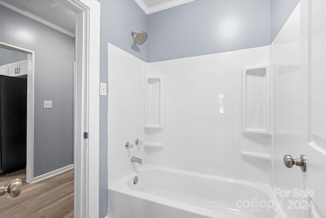 bathroom with shower / bathing tub combination, crown molding, and wood-type flooring