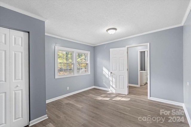 unfurnished bedroom featuring a closet, hardwood / wood-style flooring, ornamental molding, and a textured ceiling