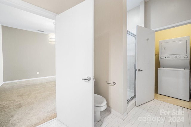 bathroom featuring stacked washing maching and dryer, an enclosed shower, tile patterned floors, and toilet