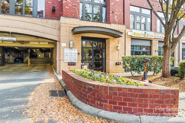 view of exterior entry featuring aphalt driveway and brick siding