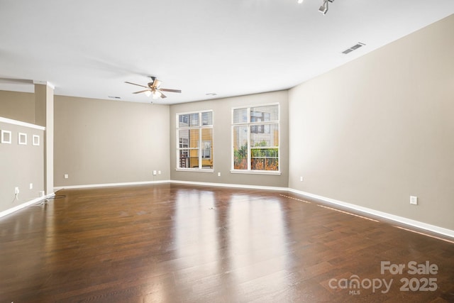 empty room with baseboards, visible vents, ceiling fan, and wood finished floors