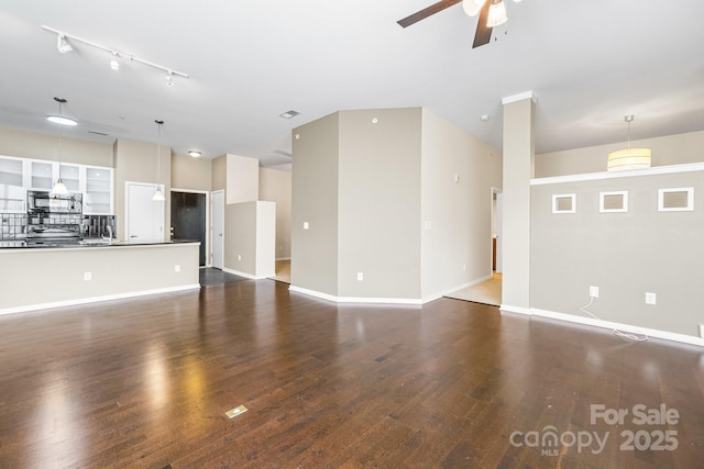 unfurnished living room with baseboards, visible vents, ceiling fan, and dark wood-style flooring