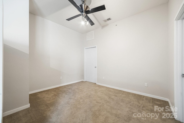 carpeted spare room with baseboards, ceiling fan, and visible vents