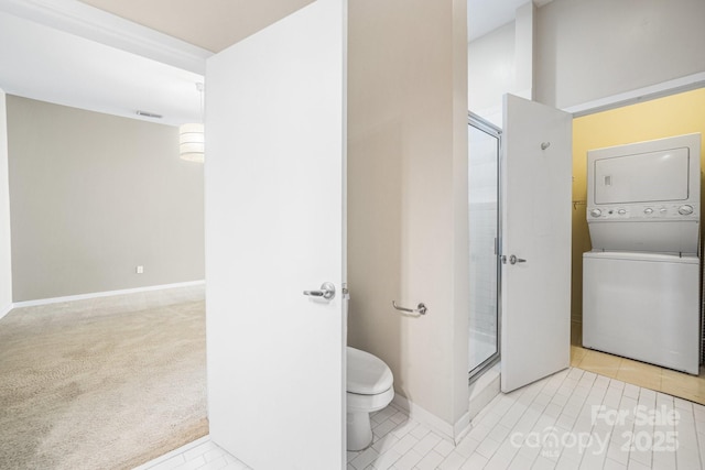 full bathroom featuring tile patterned flooring, stacked washer and clothes dryer, toilet, baseboards, and a shower stall