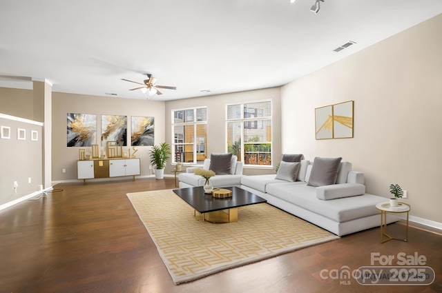living area featuring baseboards, visible vents, wood finished floors, and a ceiling fan