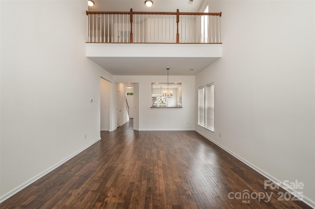 interior space featuring a towering ceiling, dark hardwood / wood-style floors, and a chandelier