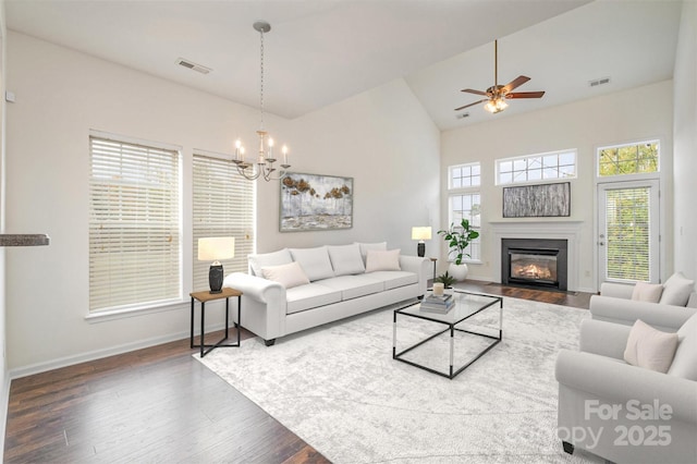 living room with hardwood / wood-style flooring, ceiling fan with notable chandelier, and high vaulted ceiling