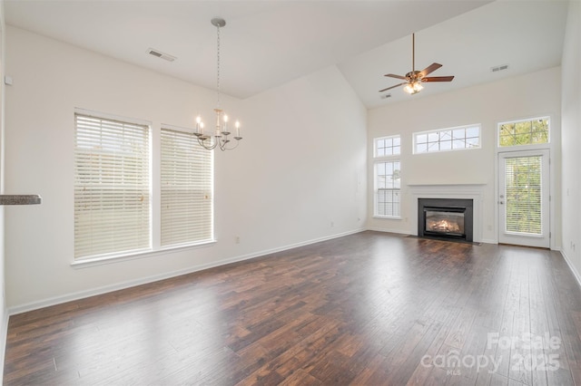 unfurnished living room with dark wood-type flooring, high vaulted ceiling, and ceiling fan with notable chandelier