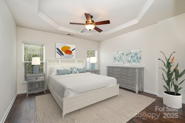 bedroom with multiple windows, crown molding, dark wood-type flooring, and a tray ceiling