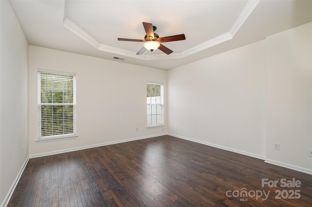 spare room featuring dark wood-type flooring, ornamental molding, a tray ceiling, and a wealth of natural light