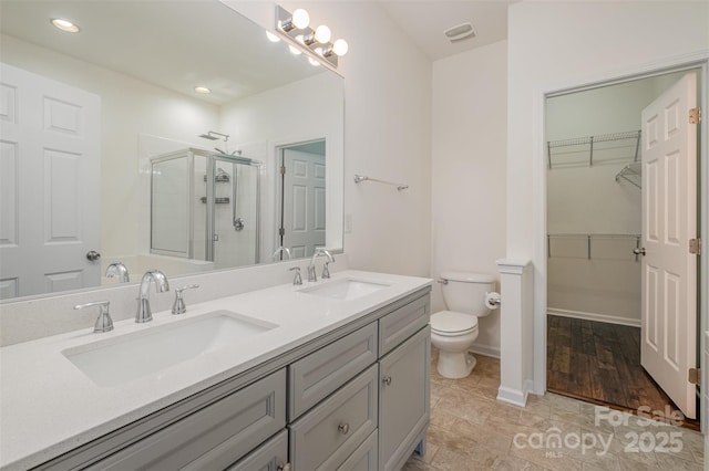 bathroom with toilet, vanity, and a shower with shower door