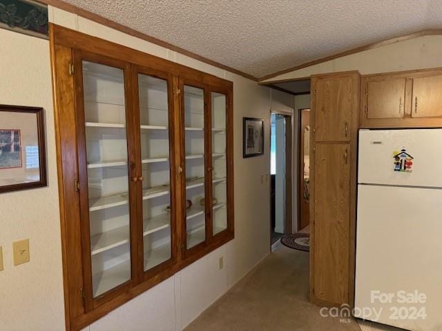 interior space featuring vaulted ceiling, white fridge, a textured ceiling, and light colored carpet