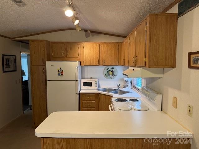 kitchen featuring lofted ceiling, exhaust hood, kitchen peninsula, a textured ceiling, and white appliances