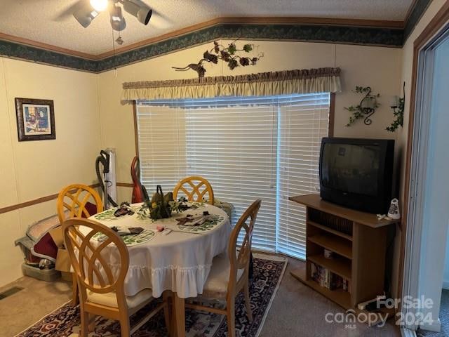 carpeted dining space with lofted ceiling, crown molding, a textured ceiling, and ceiling fan