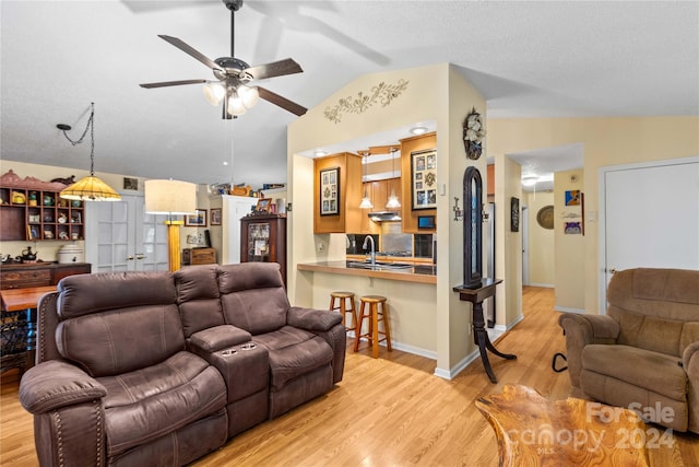 living room with ceiling fan, sink, light hardwood / wood-style flooring, and vaulted ceiling