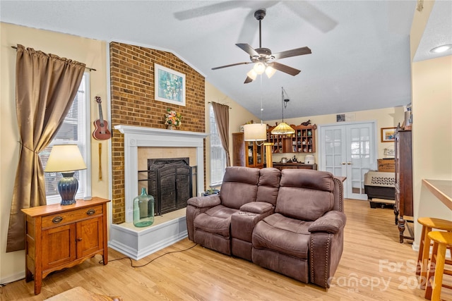 living room with a brick fireplace, light hardwood / wood-style flooring, ceiling fan, and lofted ceiling