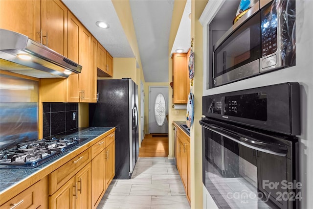 kitchen featuring black appliances, decorative backsplash, and light hardwood / wood-style flooring