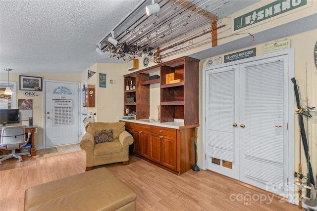 living room with a textured ceiling, light hardwood / wood-style floors, and vaulted ceiling