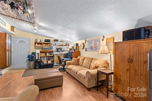 living room with light hardwood / wood-style floors, lofted ceiling, and a textured ceiling