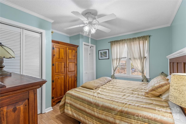 bedroom with a textured ceiling, two closets, ceiling fan, crown molding, and light hardwood / wood-style floors