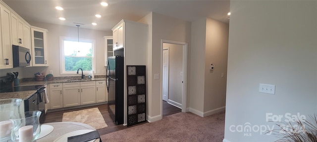 kitchen featuring stone counters, black appliances, sink, decorative light fixtures, and white cabinets