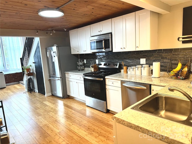 kitchen featuring sink, backsplash, stainless steel appliances, white cabinets, and light hardwood / wood-style flooring