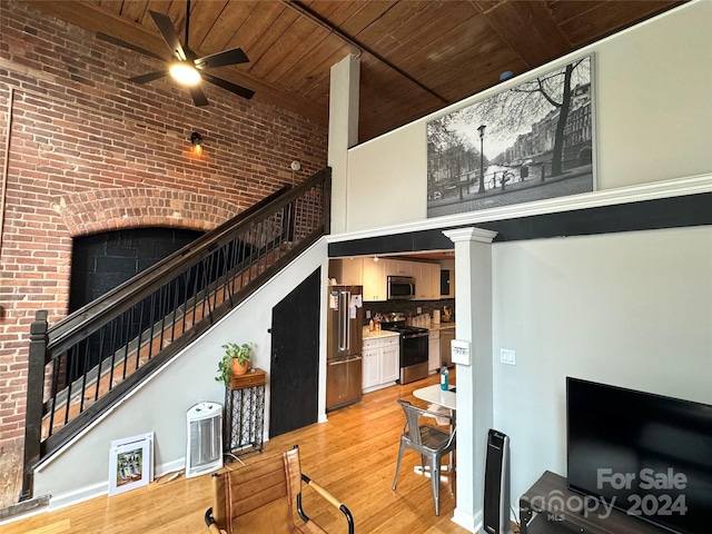 living room with wood ceiling, ornate columns, light wood-type flooring, a towering ceiling, and ceiling fan