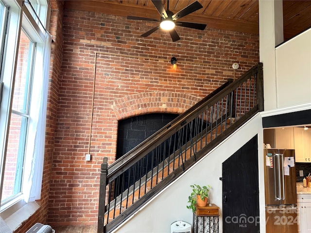 stairs featuring a towering ceiling, wood ceiling, beam ceiling, and plenty of natural light