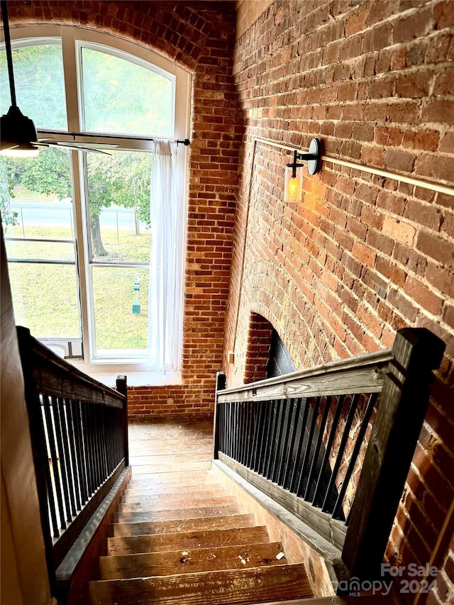 stairway featuring brick wall and wood-type flooring