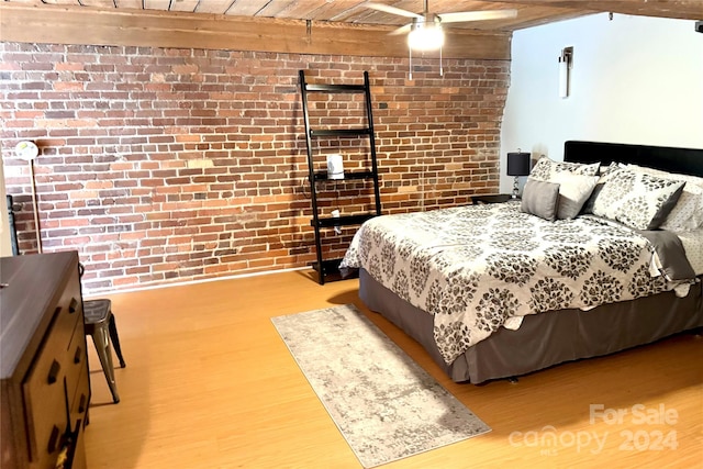 bedroom with wood ceiling, beamed ceiling, brick wall, light wood-type flooring, and ceiling fan