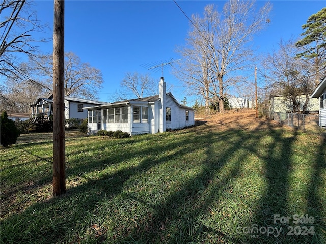 view of property exterior with a sunroom and a yard