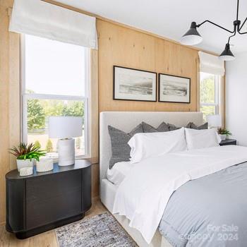 bedroom featuring light hardwood / wood-style flooring, multiple windows, and an inviting chandelier